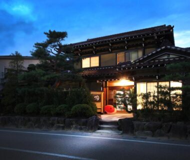 Dusk exterior with lit entrance, stone path and pine, Ichinomatsu Japanese Modern Hotel, Gifu Chūbu Japan