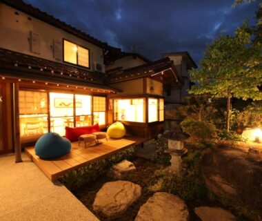 Evening view of lit wooden terrace, stone garden and pond at Ichinomatsu Japanese Modern Hotel in Gifu, Chūbu