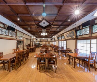 Spacious ryokan dining hall with wooden tables, shoji screens and coffered ceiling at Ichinoyu Honkan, Kanagawa