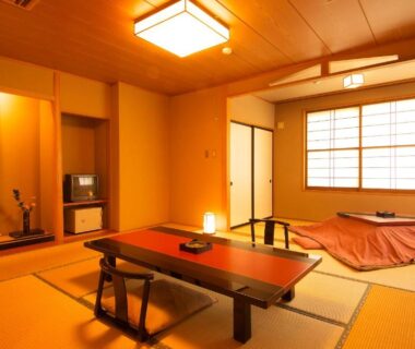 Traditional tatami room with low dining table, shoji screens and tokonoma alcove at Ichinoyu Katei in Nagano