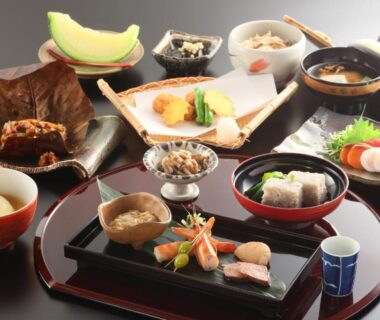 Assorted Japanese dishes on lacquer trays including sashimi and soup bowls