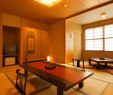 Tatami room with low table, zabuton cushions, tokonoma and shoji screens at Ichinoyu Katei in Nagano, Chūbu