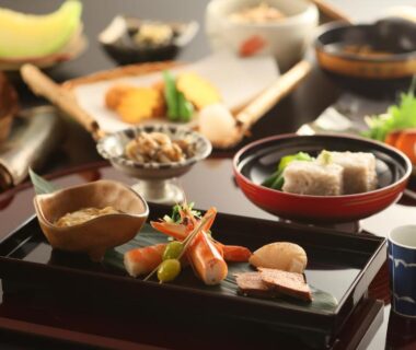 Assorted small dishes on lacquer tray in ryokan dining setting at Ichinoyu Katei Nagano