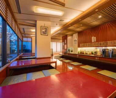 Low red lacquer tables on tatami with zabuton cushions and a long beverage counter in Fukushima ryokan dining room