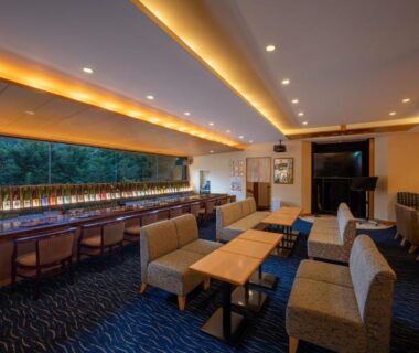 Warm lounge with sofas and counter seating facing green landscape at Iizaka Onsen Surikamitei Ohtori, Fukushima