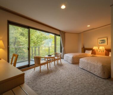 Twin beds and balcony overlooking green trees at Iizaka Onsen Surikamitei Ohtori Fukushima