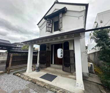 Kura-style white plaster entrance with wooden lattices and hanging lantern at Iizukatei in Tochigi