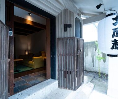 Wooden gate and white lantern at Iizukatei entrance in Tochigi revealing a tatami room with low seating