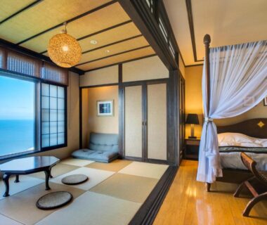 Tatami seating, low table and canopy bed by large sea-facing window with shoji screens at Ijika Daiichi Kagura, Mie