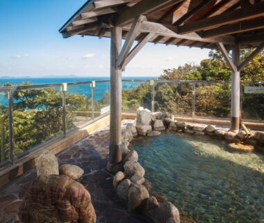Outdoor onsen bath with rock edging and sea view at Ijika Daiichi Hotel Kagura Mie