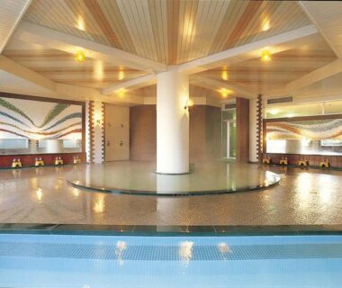 Spacious indoor onsen bath with central pillar and mosaic walls at Ikaho Grand Hotel, Gunma, Japan
