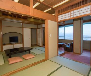Tatami room with low table, floor cushions, shoji screens and window seating at Ikaho Grand Hotel, Gunma