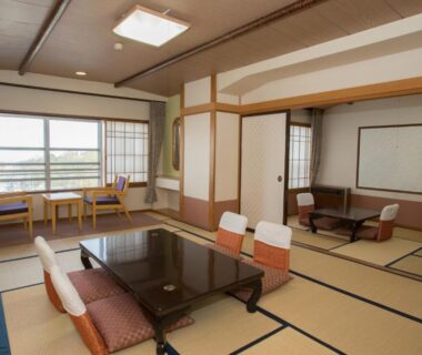 Spacious tatami room with low table, floor chairs, shoji screens and window seating at Ikaho Onsen Todoroki