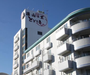 White multi-story ryokan building with curved balconies and rooftop signage in Ikaho Onsen, Gunma, Kantō