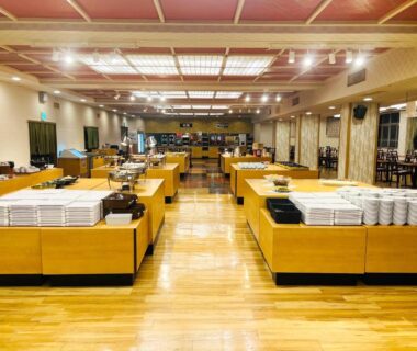 Spacious buffet hall with wooden floors, stacked plates and serving stations at Ikaho Onsen Todoroki in Gunma