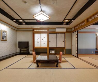 Spacious tatami room with low wooden table, two floor chairs, shoji sliding doors at Ikaho Onsen Todoroki in Gunma