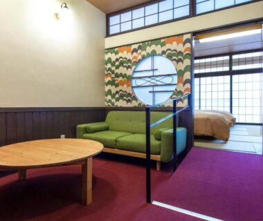 Low round table, green sofa, shoji screens and futon area in a guest room at Ikaho Syusuien, Gunma