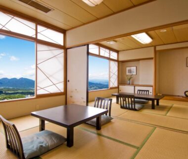 Spacious tatami room with low tables, shoji screens and mountain view at Ikaho Syusuien in Gunma