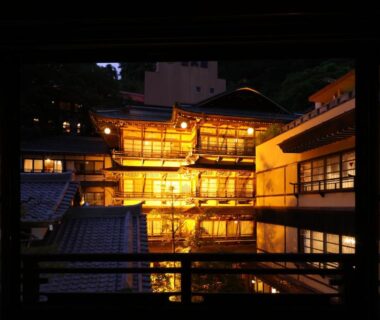 Night view through window of illuminated wooden ryokan exterior at Ikariya Ryokan in Nagano, Chūbu region, Japan