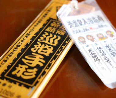 Wooden admission token and paper tag with Japanese text on lacquered wooden table