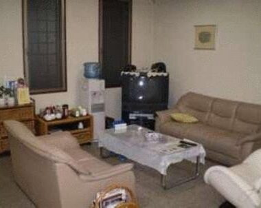 Seating area with sofas, coffee table, TV and water dispenser in Ikawa Ryokan common lounge, Hiroshima
