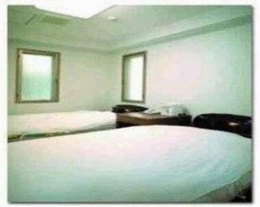 Two single beds with white linens and bedside table at Ikawa Ryokan, Chūgoku Hiroshima Japan