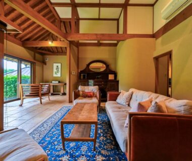 Tatami room with low wooden table, sofas, exposed beams and sliding doors to garden, Ikkoten, Ōita