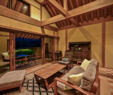 Spacious wooden lounge with exposed beams, seating and open veranda at Ikkoten in Oita, Kyushu