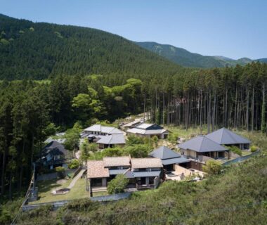 Aerial view of traditional ryokan buildings at Ikkoten amid forested hills in Ōita, Kyūshū