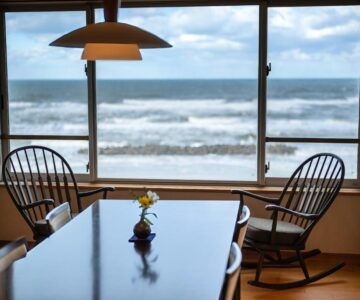 Dining table and rocking chairs by window with waves visible at Ikkyu Seaside Hotel, Yamagata