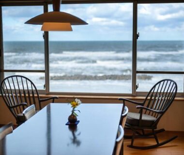 Dining table and rocking chairs by window with waves visible at Ikkyu Seaside Hotel, Yamagata
