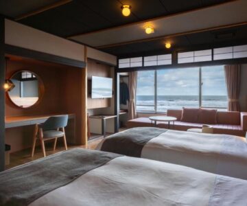 Twin beds and seating area facing sea at Ikkyu -Seaside Hotel- in Yamagata, Tōhoku