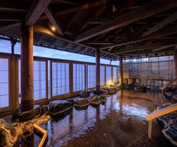 Indoor rock-lined onsen bath with shoji screens at Ikkyu -Seaside Hotel- in Yamagata