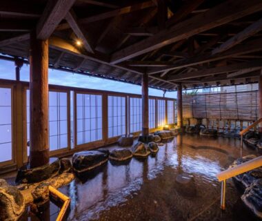 Indoor rock-lined onsen bath with shoji screens at Ikkyu -Seaside Hotel- in Yamagata