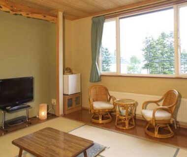 Tatami room with low table, rattan chairs and window view at Ikoiso, Hokkaidō, Japan
