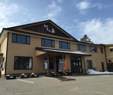 Two-story ryokan exterior Ikoiso in Hokkaidō with parking and snow patches