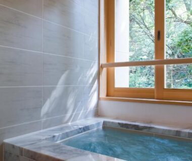 Indoor marble soaking tub by wooden window overlooking greenery at Ikyu Reopening, Mie, Japan