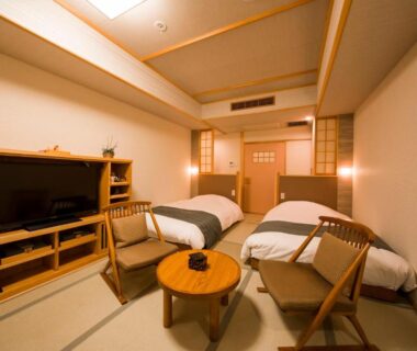 Tatami guest room with two beds, low table and chairs, warm lighting at Ikyu in Mie, Kansai