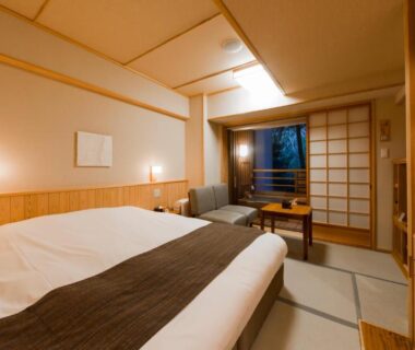 Tatami room with Western-style bed, shoji screens, low table and greenery outside at Ikyu Reopening, Mie, Kansai
