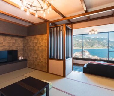 Tatami room with low table and large window overlooking coastal bay in Inatori, Shizuoka