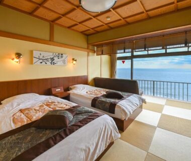 Twin beds on tatami with in-room tub and balcony overlooking the sea