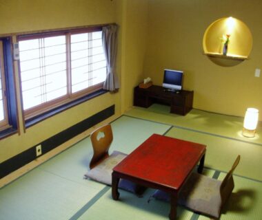 Tatami room with low wooden table, floor chairs, shoji windows and alcove at Inn Kawashima Kyoto