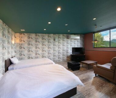 Modern twin bedroom with sofa, TV and large window with distant mountain view at Innter Hill Tsubasa Yufuin Ōita