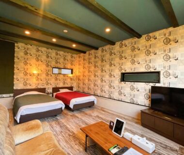 Two beds, low wooden table, sofa, patterned wallpaper and TV at Innter Hill Tsubasa Yufuin in Oita