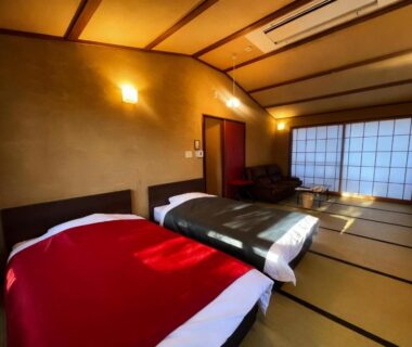 Ryokan room interior with tatami flooring, twin beds, shoji doors, low seating and warm ambient lighting