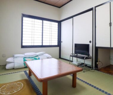 Japanese tatami room with low table, folded futons, shoji window and television at Iris Yu, Iwate