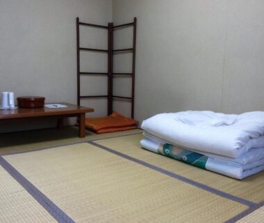 Tatami mats with folded futon, low table and cushions in a ryokan room at Iris Yu, Iwate