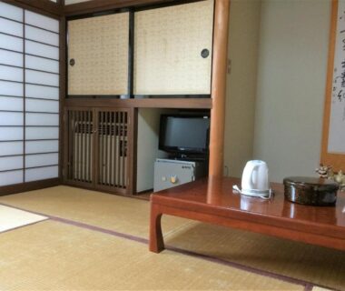 Traditional tatami room with low wooden table, shoji screens, built-in cabinet, small TV and kettle at Iris Yu Iwate
