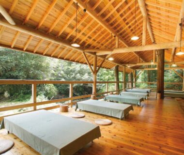 Covered wooden veranda with low platforms and floor cushions overlooking lush forest at Irori Houraku Hyōgo