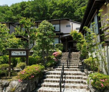Stone steps entrance with handrail, landscaped shrubs and traditional buildings at Irorino Yado Sankichi in Shizuoka